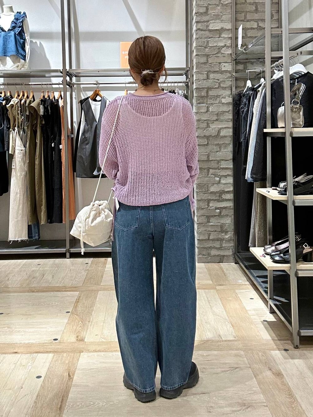 ブラック系のスニーカー、ブルー系のデニムパンツ、ブラック系のショルダーバッグを着用したレディースの春コーディネートの3枚目の写真