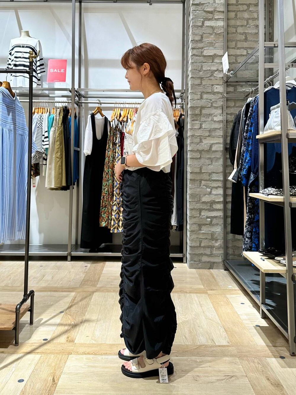 ホワイト系のサンダル、ブラック系のスカート、ホワイト系のTシャツ/カットソーを着用したレディースの夏コーディネートの2枚目の写真