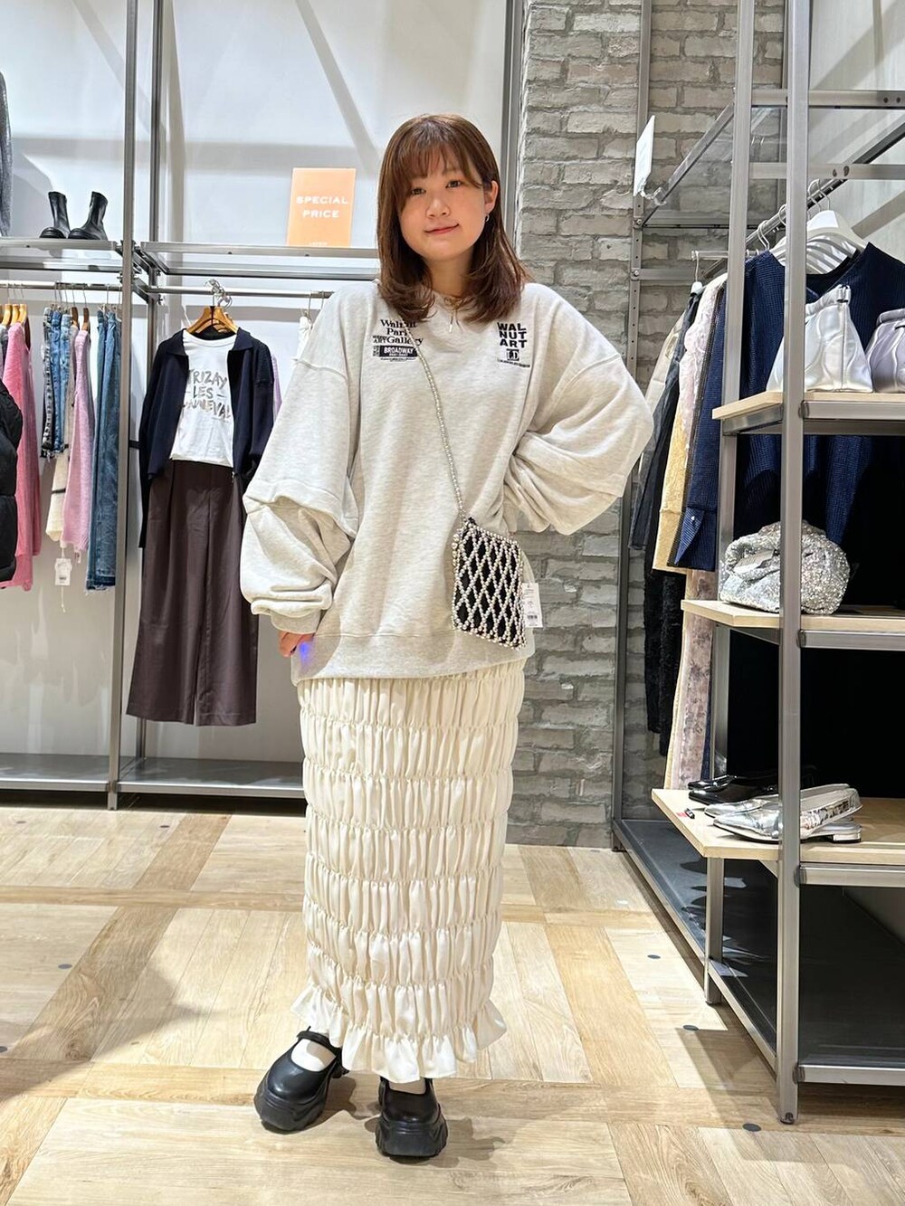 ブラック系のスニーカー、ホワイト系のスカート、ベージュ系のTシャツ/カットソーを着用したレディースの秋コーディネートの2枚目の写真