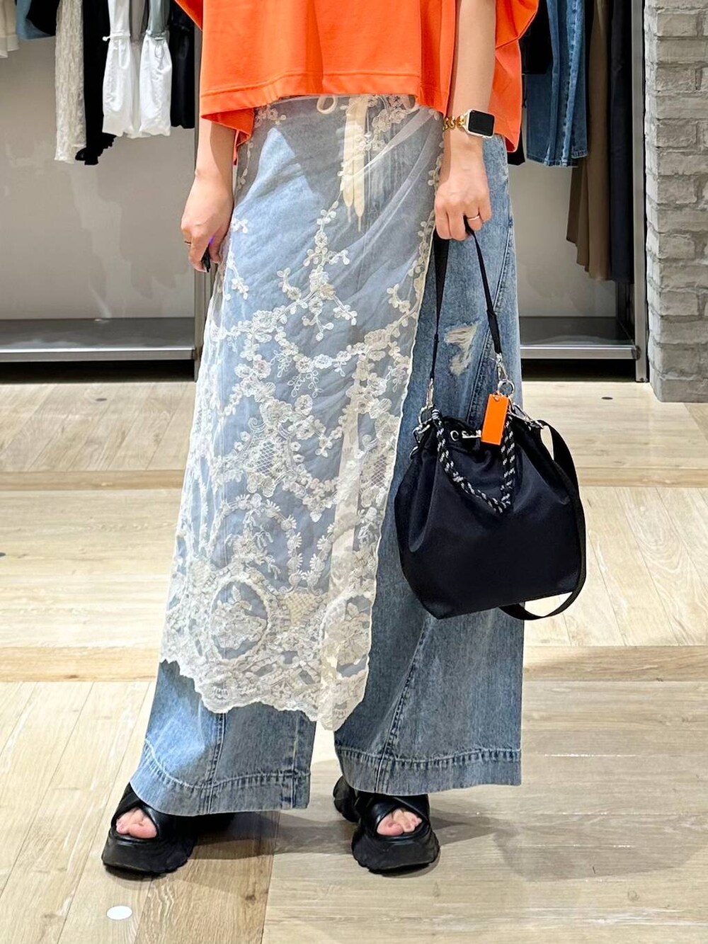 ブラック系のサンダル、オレンジ系のTシャツ/カットソー、ブルー系のデニムパンツを着用したレディースの夏コーディネートの5枚目の写真