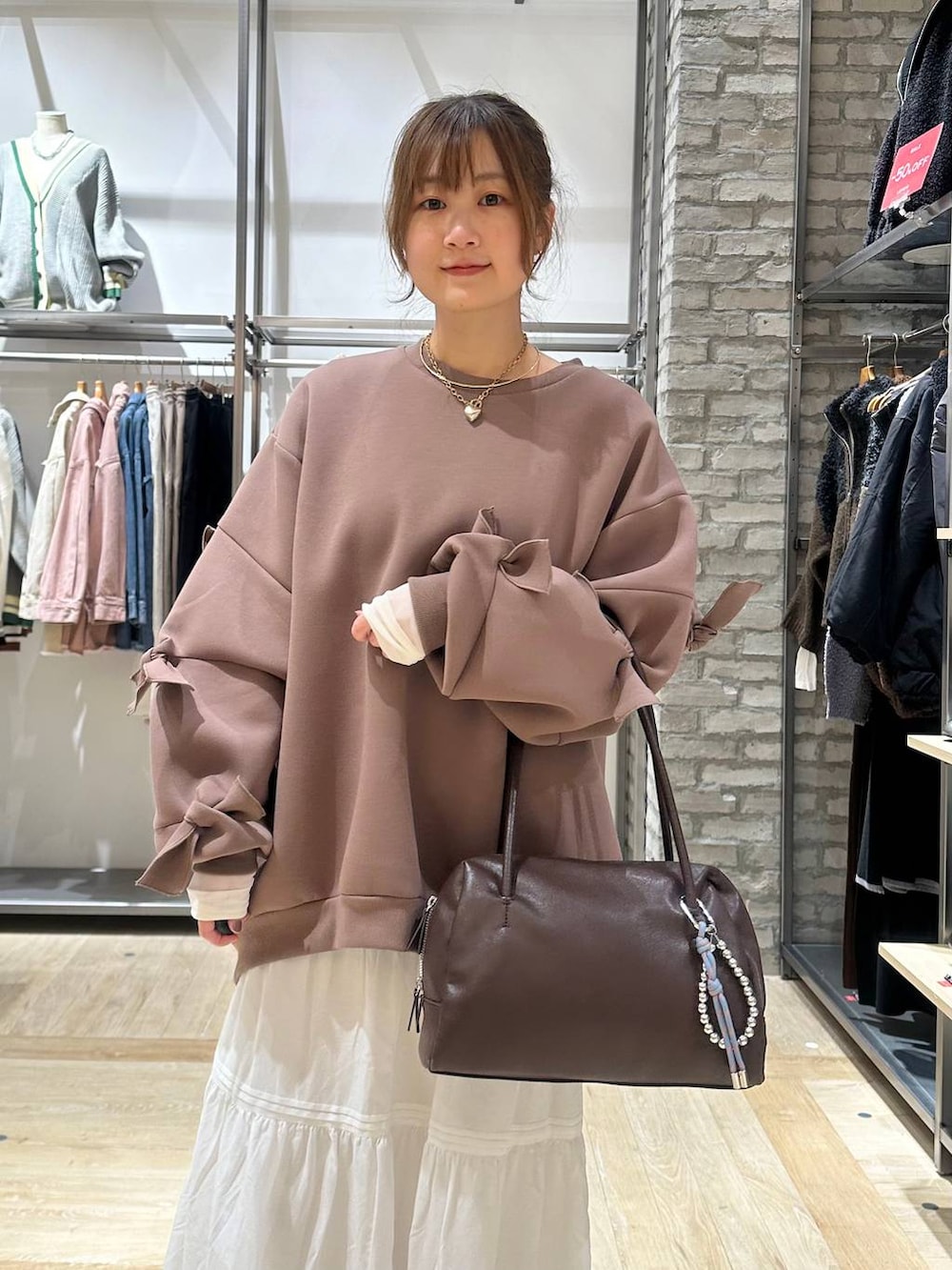 ブラウン系のスウェット、ホワイト系のTシャツ/カットソー、ブラック系のボストンバッグを着用したレディースの冬コーディネートの4枚目の写真