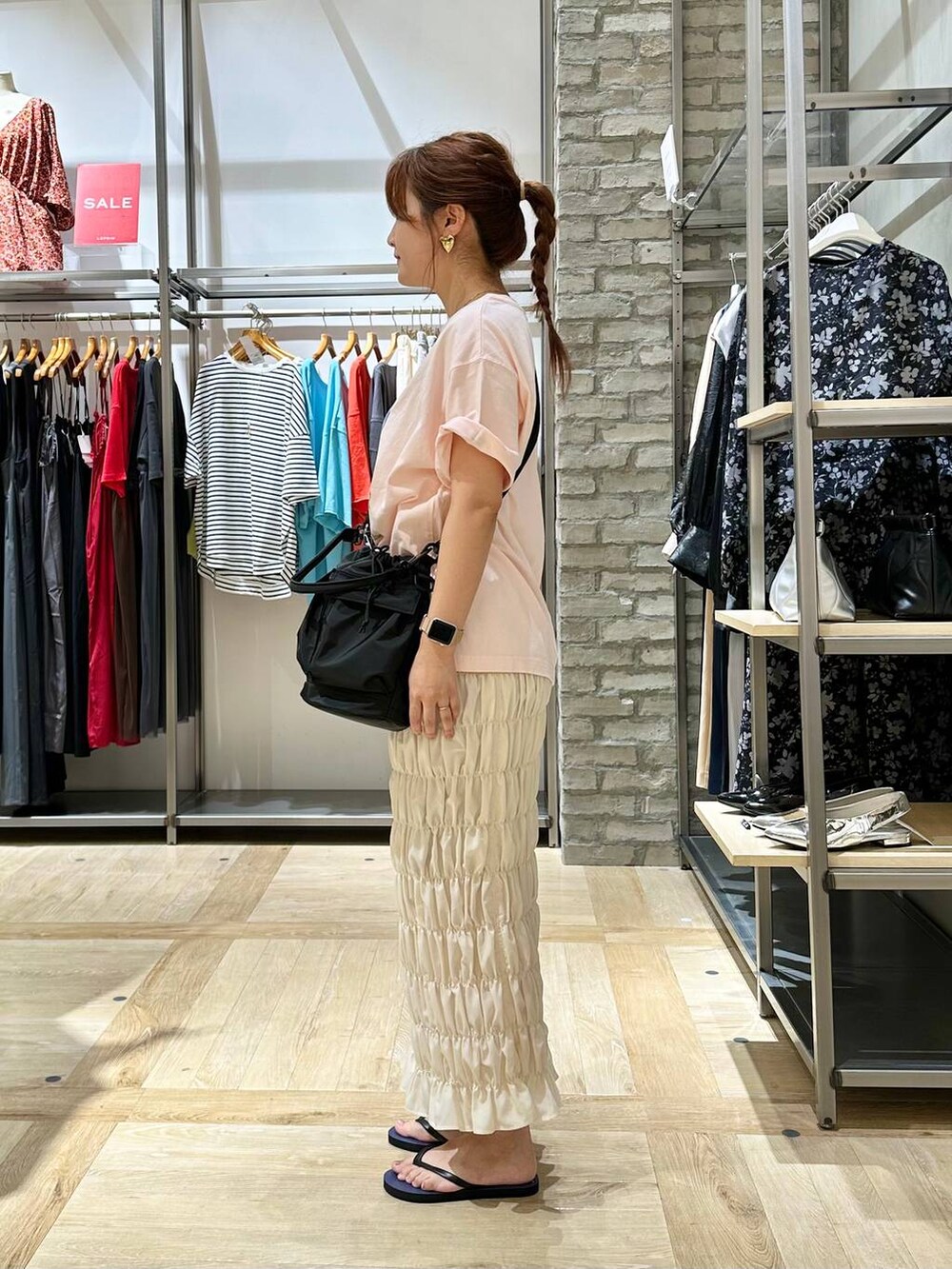 ブラック系のショルダーバッグ、ホワイト系のスカート、ベージュ系のTシャツ/カットソーを着用したレディースの夏コーディネートの2枚目の写真