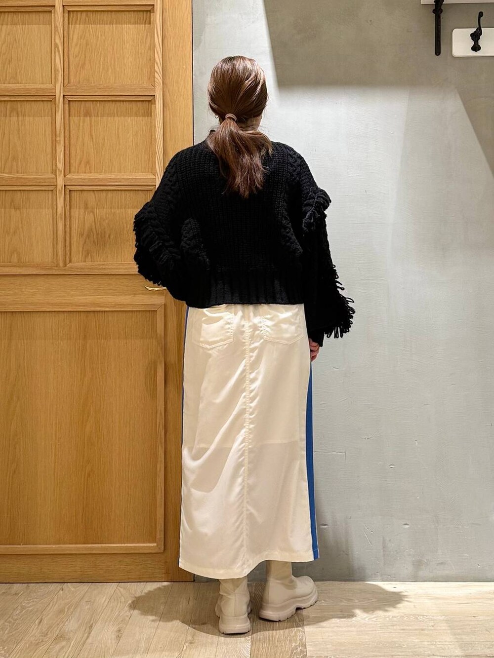 ブラック系のニット/セーター、ホワイト系のブーツ、ホワイト系のスカートを着用したレディースの冬コーディネートの4枚目の写真