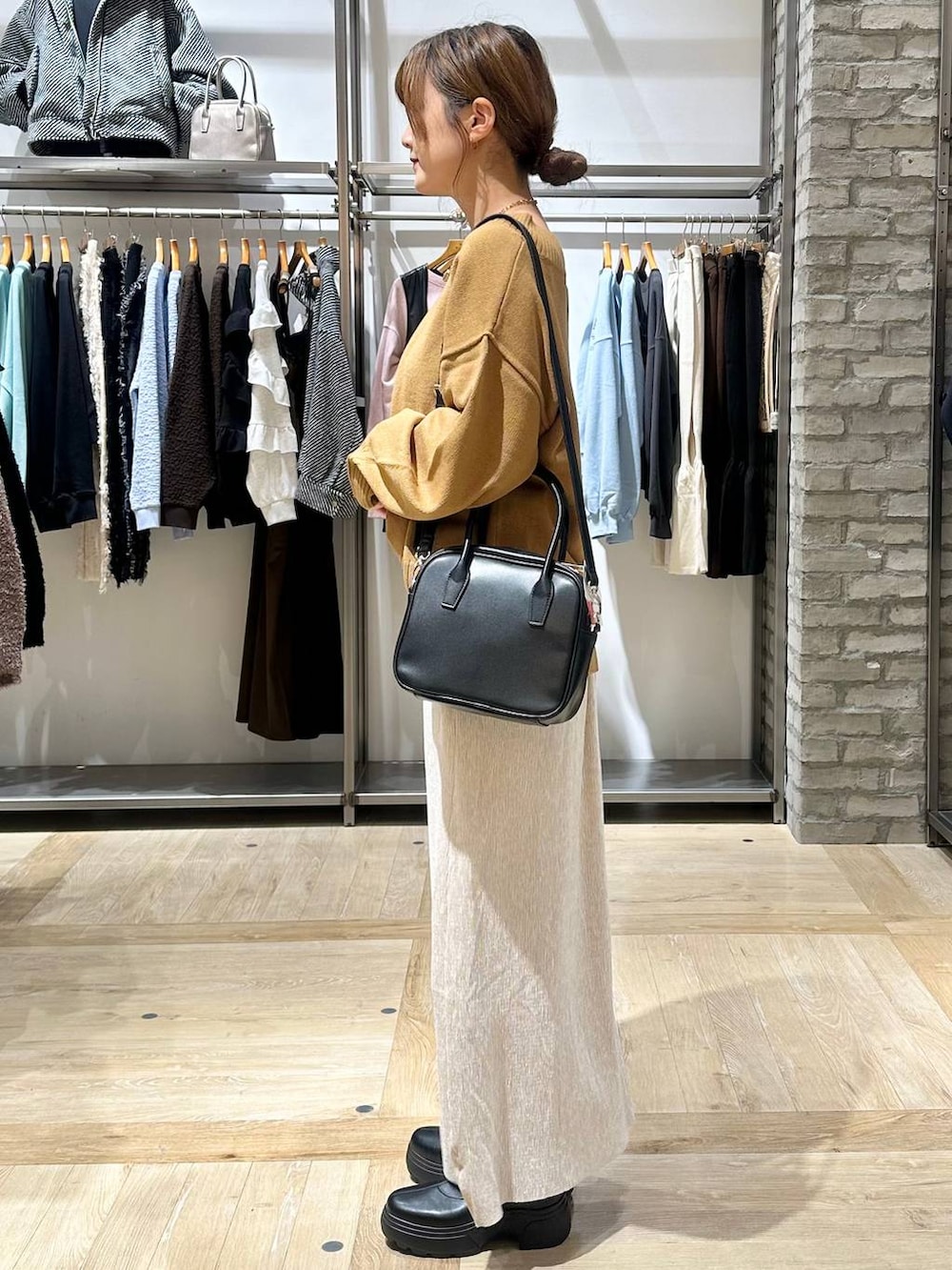 イエロー系のニット/セーター、ブラック系のボストンバッグ、ブラック系のブーツを着用したレディースの秋コーディネートの7枚目の写真