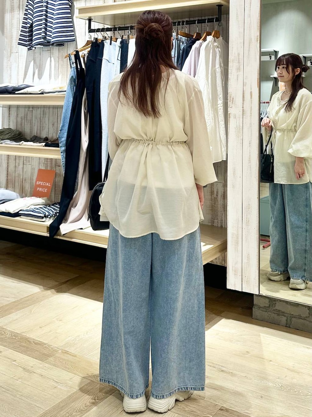 ブルー系のデニムパンツ、ブラック系のボストンバッグ、ホワイト系のシャツ/ブラウスを着用したレディースの春コーディネートの3枚目の写真