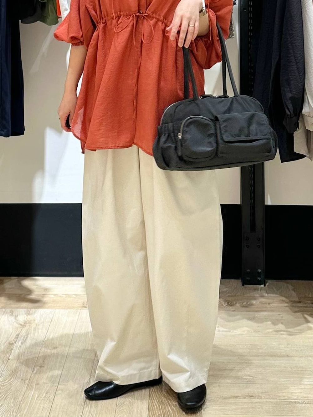 ブラック系のパンプス、オレンジ系のシャツ/ブラウス、グレー系のボストンバッグを着用したレディースの春コーディネートの5枚目の写真