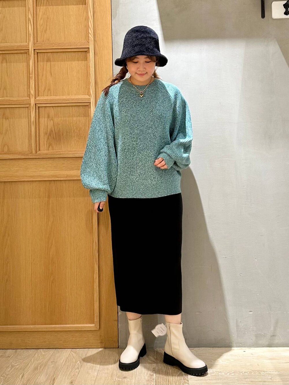 ブラック系のスカート、ホワイト系のブーツ、シルバー系のショルダーバッグを着用したレディースの秋コーディネートの2枚目の写真