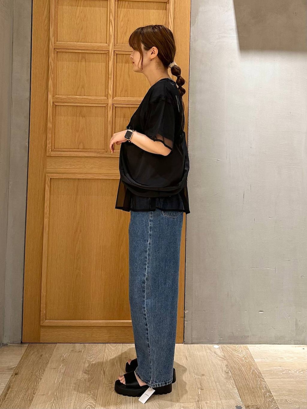 ブルー系のデニムパンツ、ブラック系のショルダーバッグ、ブラック系のTシャツ/カットソーを着用したレディースの春コーディネートの2枚目の写真