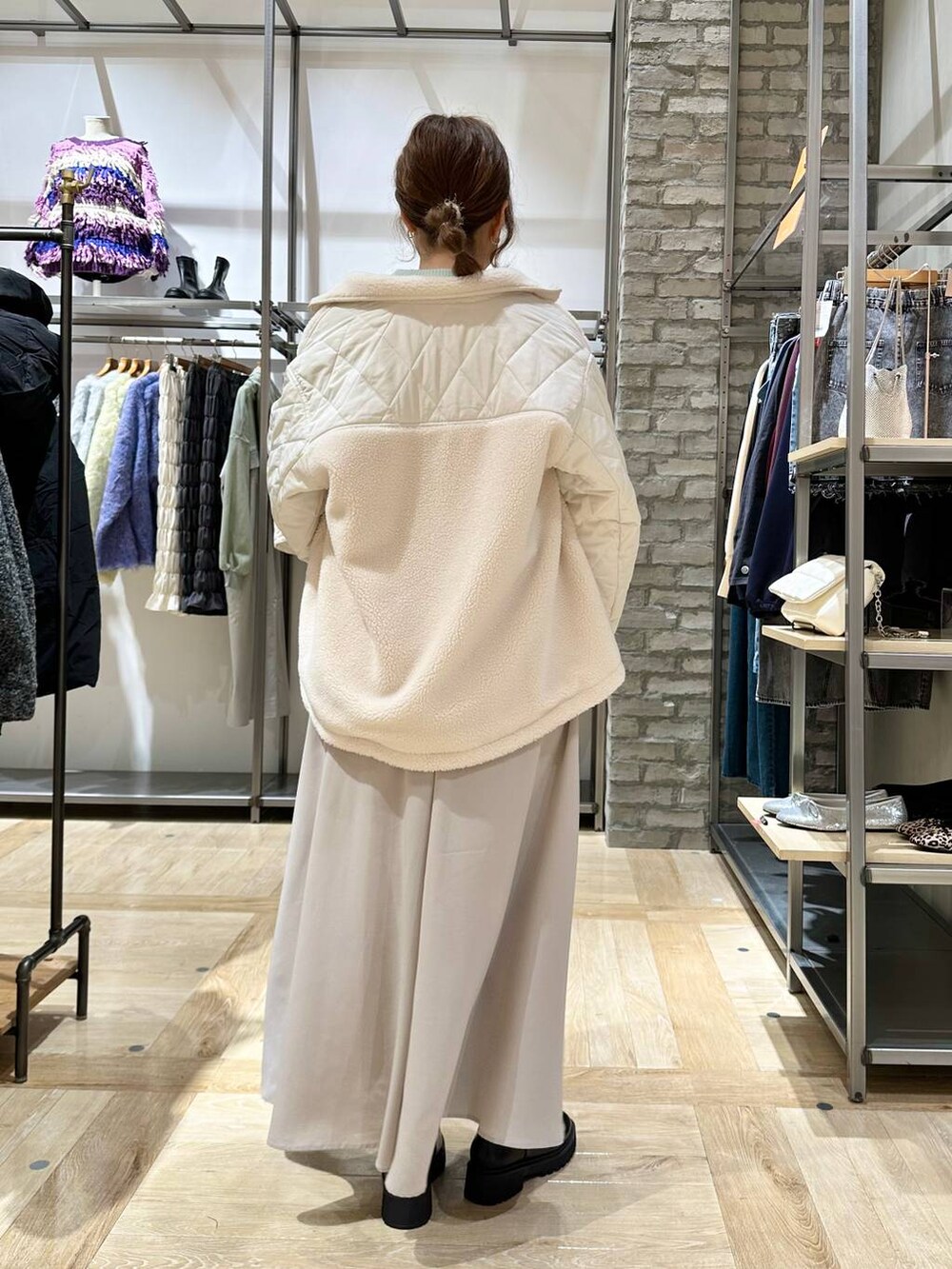 グリーン系のニット/セーター、ブラック系のブーツ、ホワイト系のブルゾンを着用したレディースの秋コーディネートの3枚目の写真