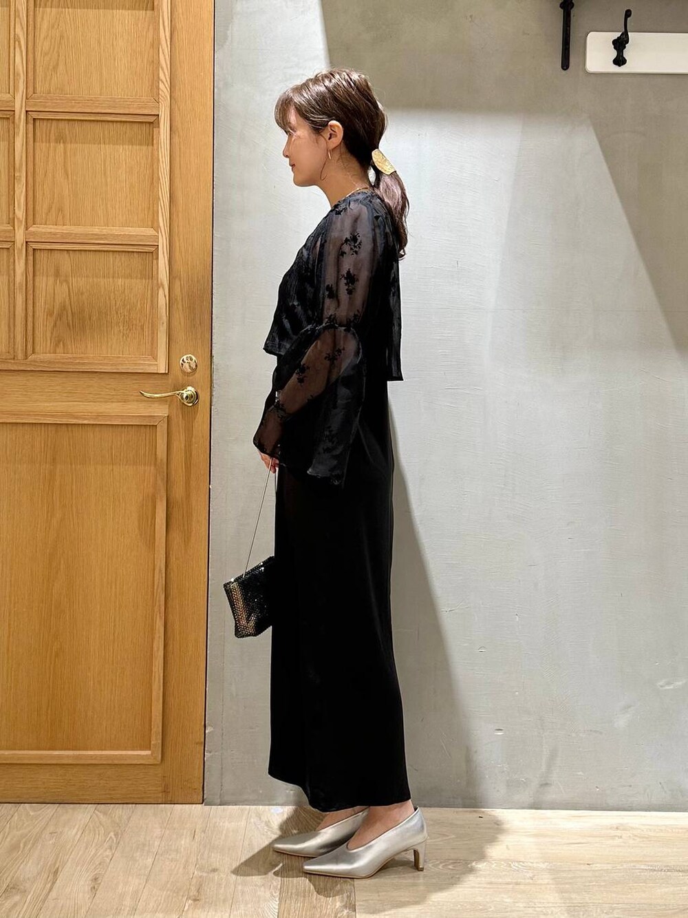 シルバー系のパンプス、ブラック系のショルダーバッグ、ブラック系のワンピースを着用したレディースの秋コーディネートの2枚目の写真