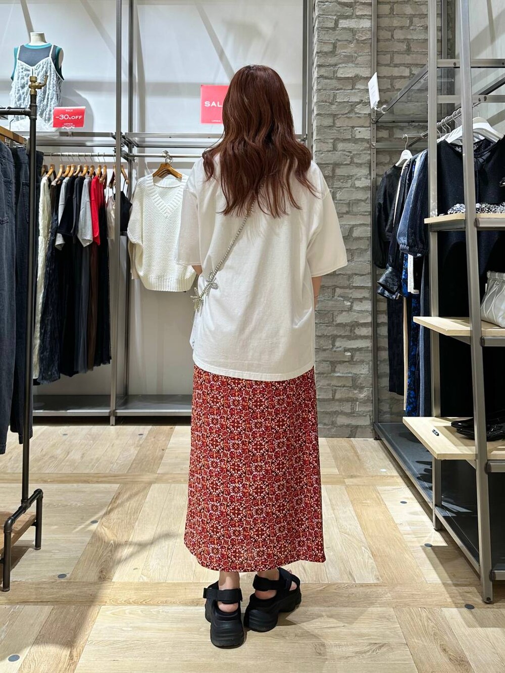 ブラック系のサンダル、レッド系のスカート、ホワイト系のTシャツ/カットソーを着用したレディースの夏コーディネートの3枚目の写真