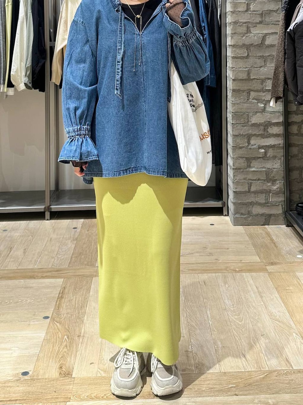 グリーン系のスカート、ブラック系のTシャツ/カットソー、ホワイト系のトートバッグを着用したレディースの冬コーディネートの6枚目の写真