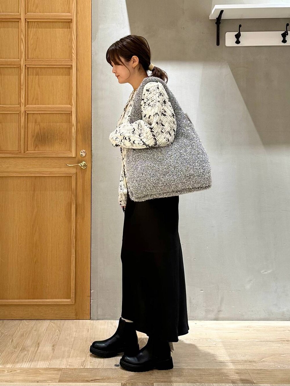 シルバー系のショルダーバッグ、ブラック系のスカート、ブラック系のブーツを着用したレディースの秋コーディネートの3枚目の写真