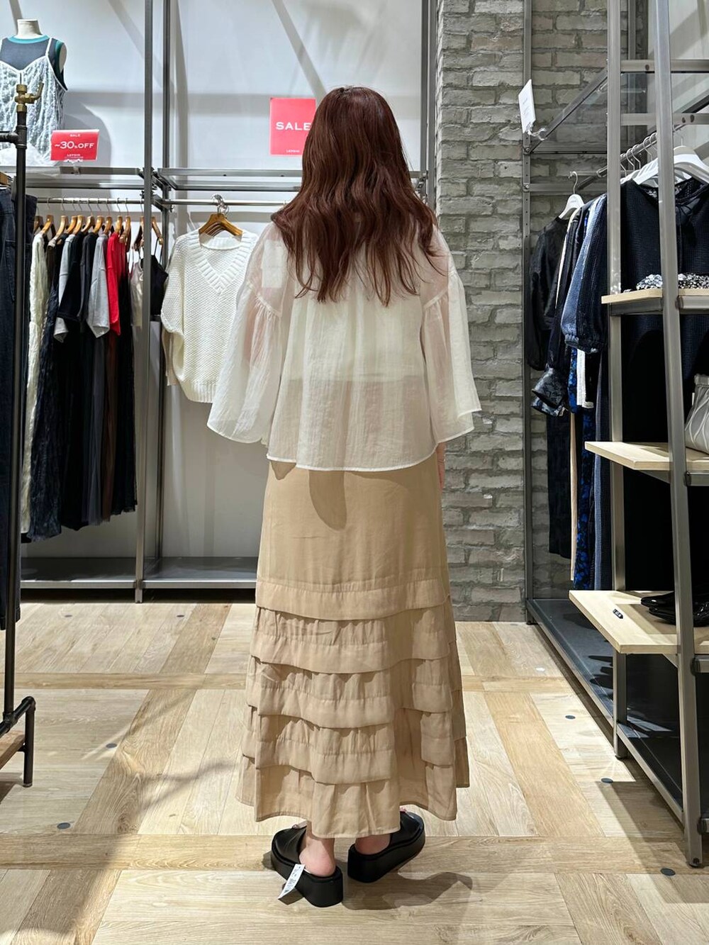 ベージュ系のスカート、ホワイト系のシャツ/ブラウス、ブラック系のサンダルを着用したレディースの夏コーディネートの4枚目の写真