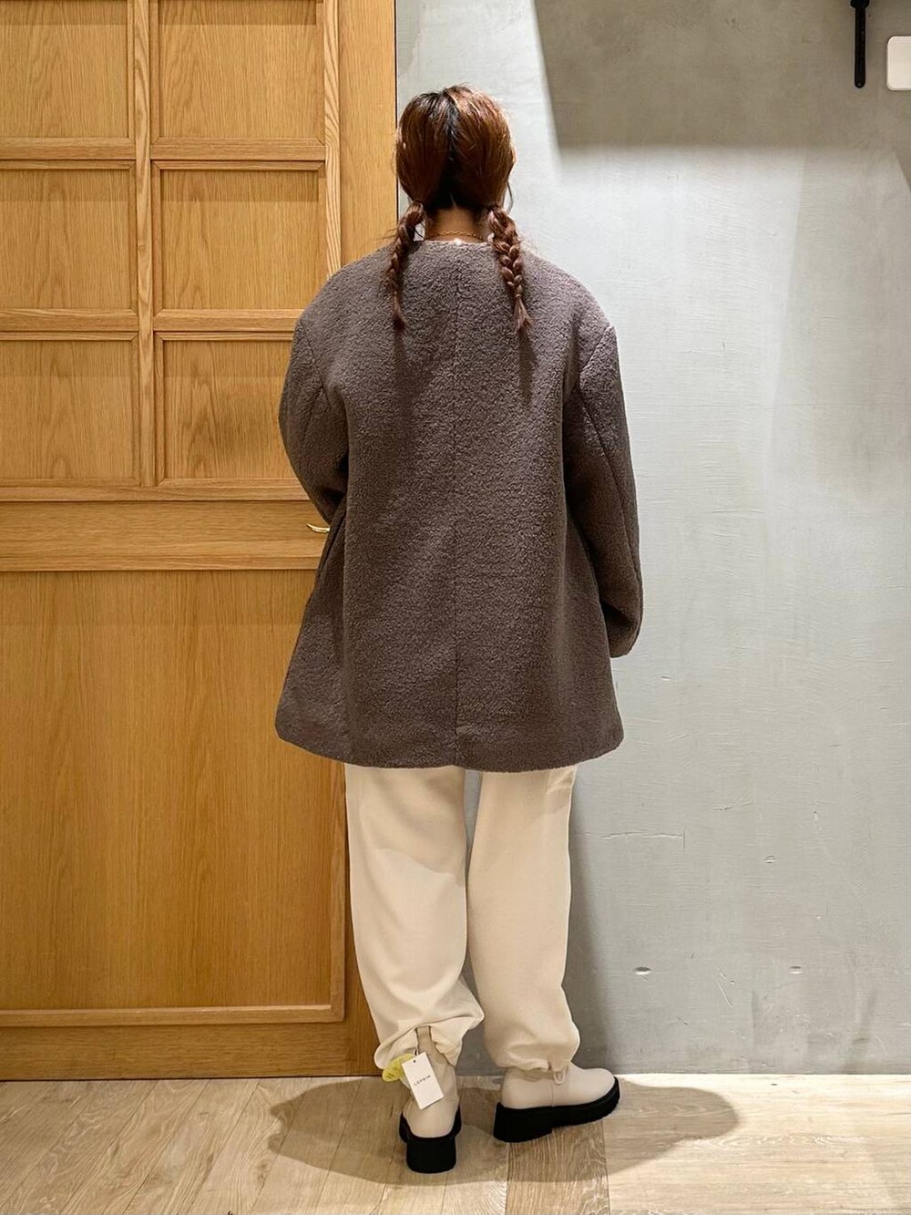 ブラウン系のノーカラーコート、ホワイト系のブーツ、ホワイト系のショルダーバッグを着用したレディースの秋コーディネートの4枚目の写真