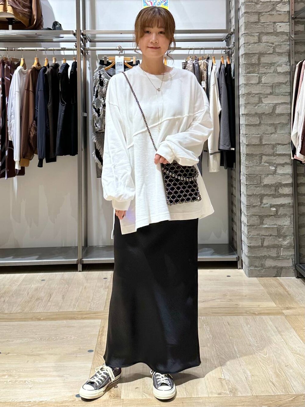 ブラック系のショルダーバッグ、ブラック系のスカート、ホワイト系のTシャツ/カットソーを着用したレディースの秋コーディネートの2枚目の写真