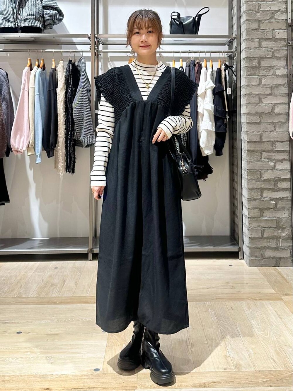 ブラック系のショルダーバッグ、ホワイト系のニット/セーター、ブラック系のブーツを着用したレディースの秋コーディネートの7枚目の写真