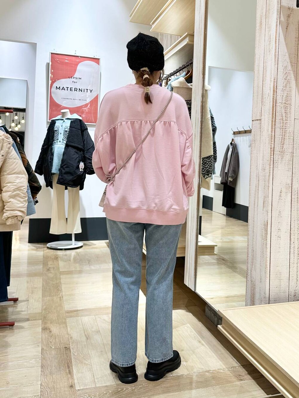 ブルー系のデニムパンツ、ブラック系のブーツ、ピンク系のスウェットを着用したレディースの冬コーディネートの4枚目の写真