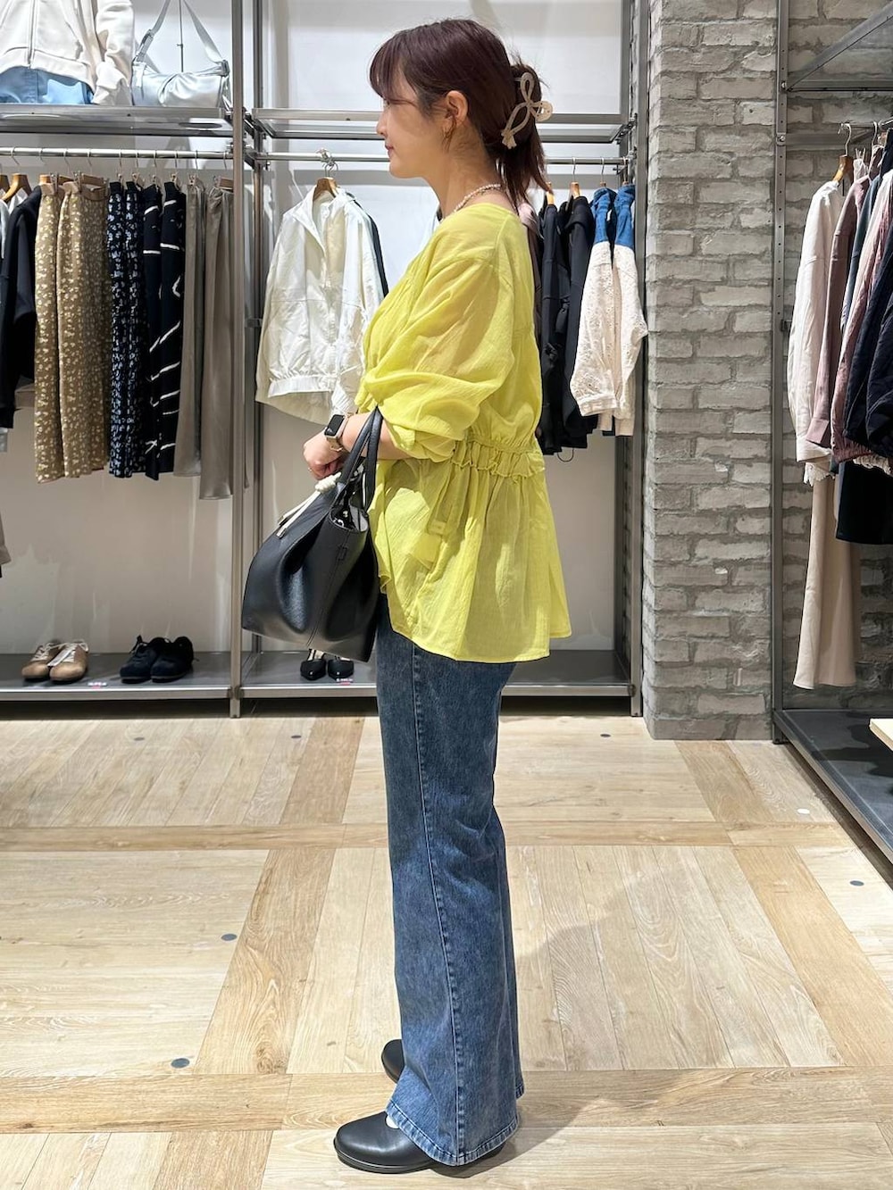 ブラック系のパンプス、ブラック系のトートバッグ、ブルー系のデニムパンツを着用したレディースの春コーディネートの2枚目の写真