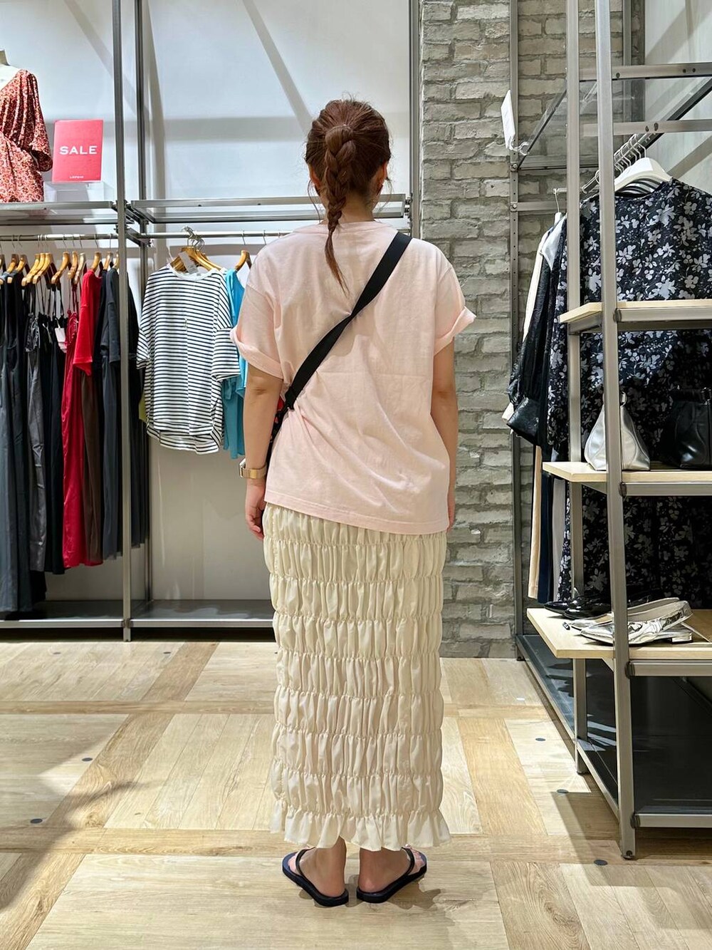 ブラック系のショルダーバッグ、ホワイト系のスカート、ベージュ系のTシャツ/カットソーを着用したレディースの夏コーディネートの3枚目の写真