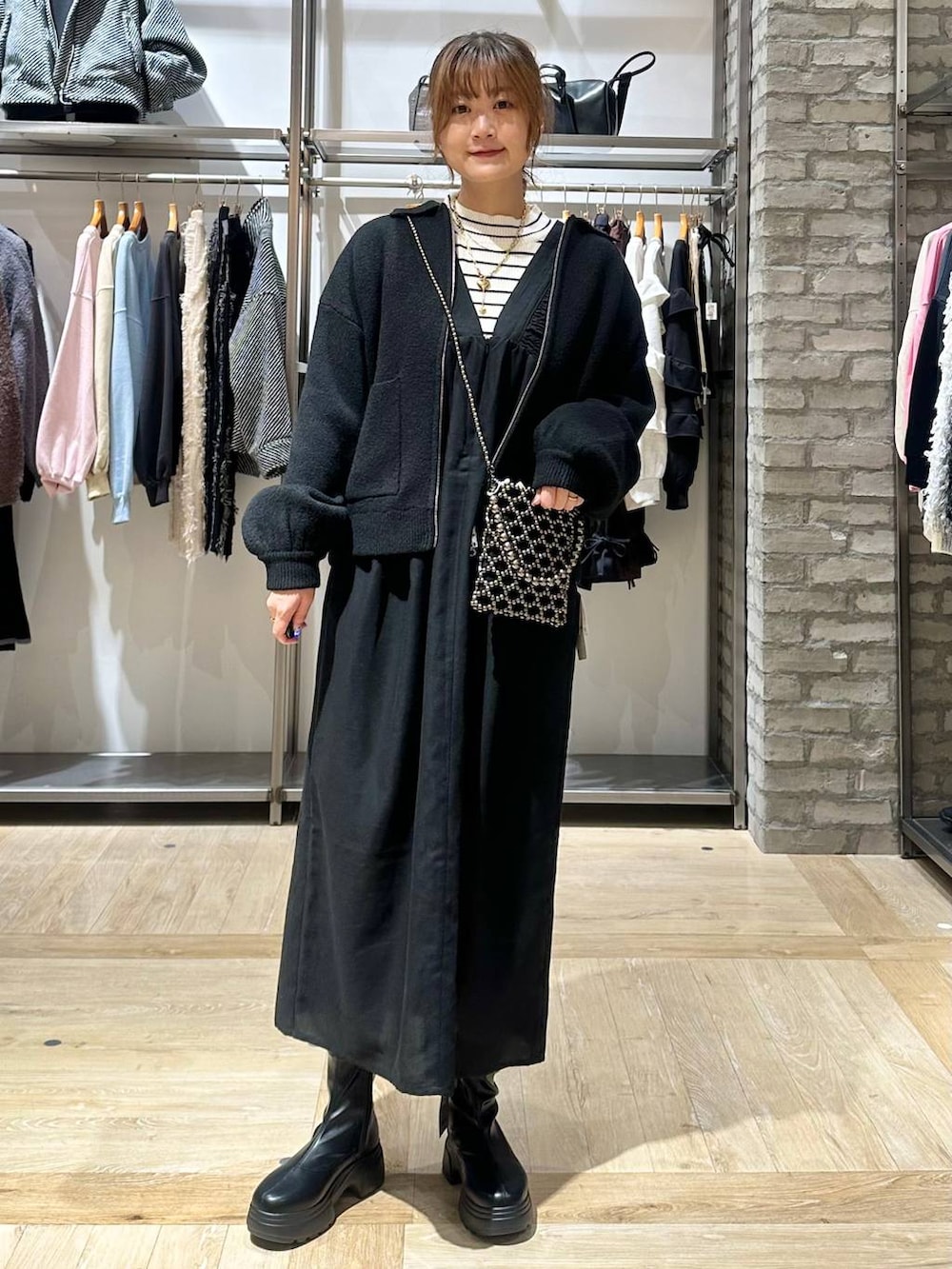 ブラック系のショルダーバッグ、ホワイト系のニット/セーター、ブラック系のブーツを着用したレディースの秋コーディネートの2枚目の写真