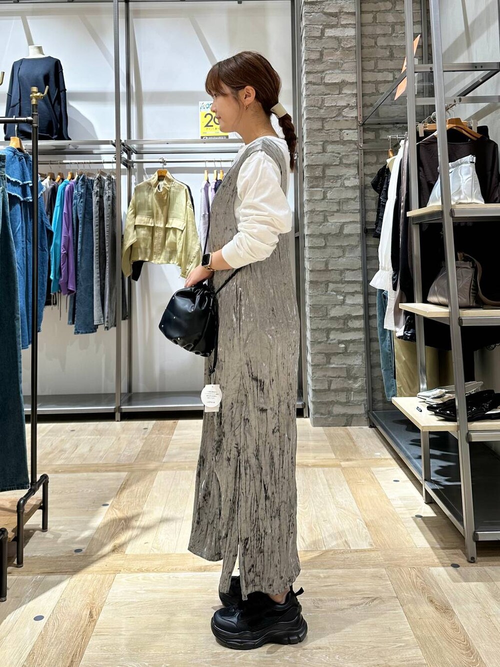ブラック系のスニーカー、ブラック系のショルダーバッグ、ホワイト系のTシャツ/カットソーを着用したレディースの秋コーディネートの2枚目の写真