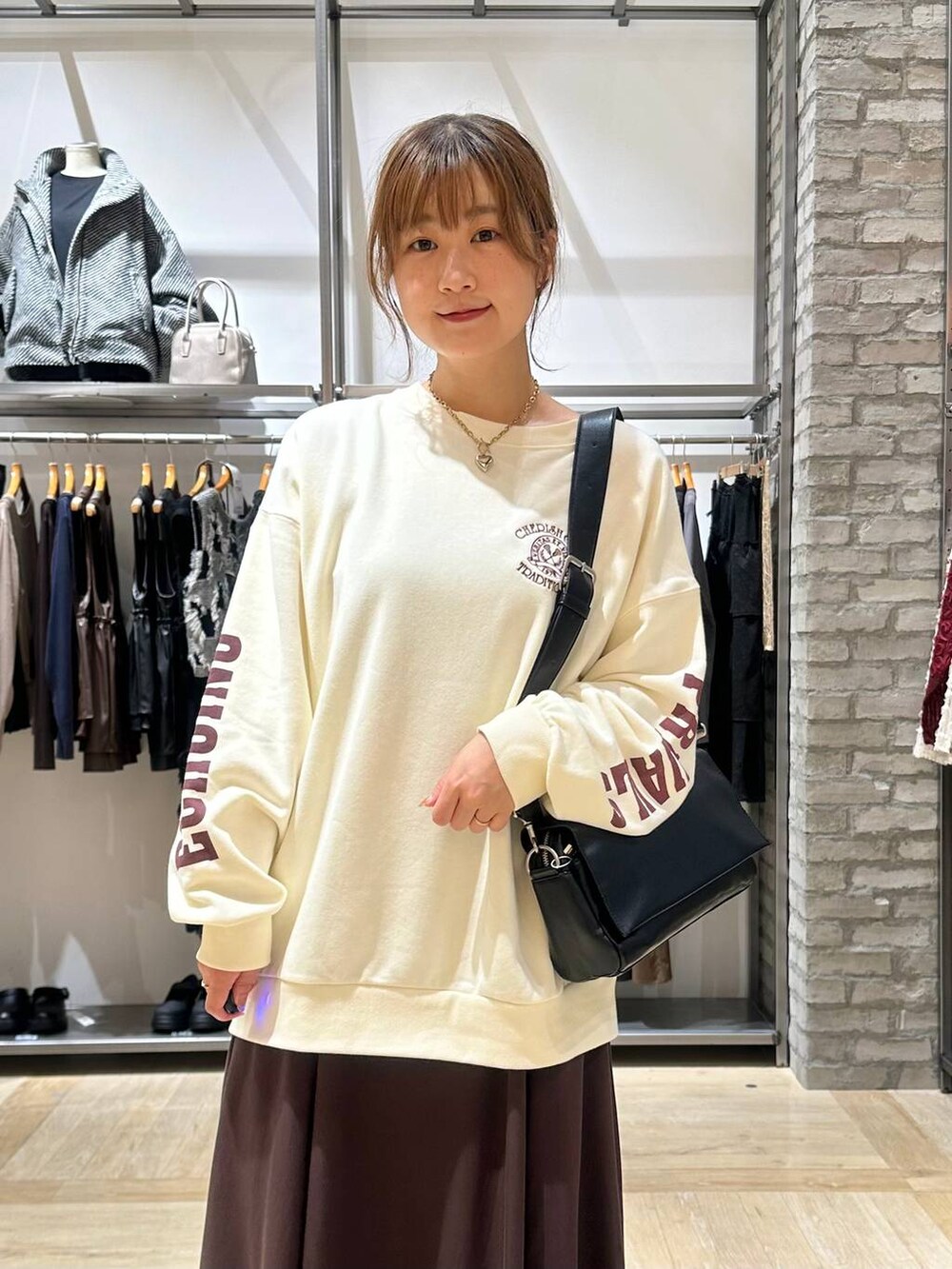 ブラック系のショルダーバッグ、ブラウン系のスカート、ブラック系のブーツを着用したレディースの秋コーディネートの4枚目の写真