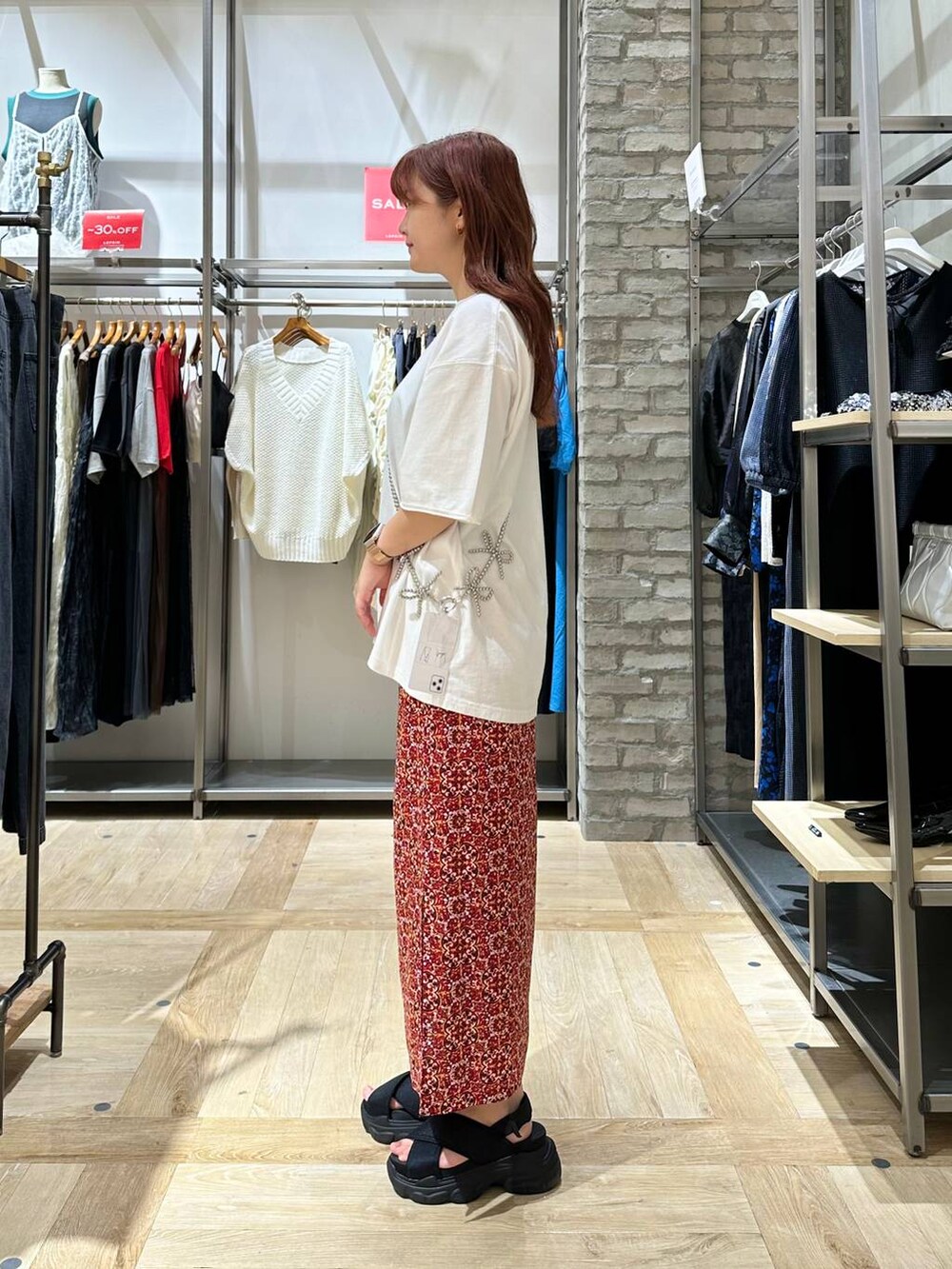 ブラック系のサンダル、レッド系のスカート、ホワイト系のTシャツ/カットソーを着用したレディースの夏コーディネートの2枚目の写真