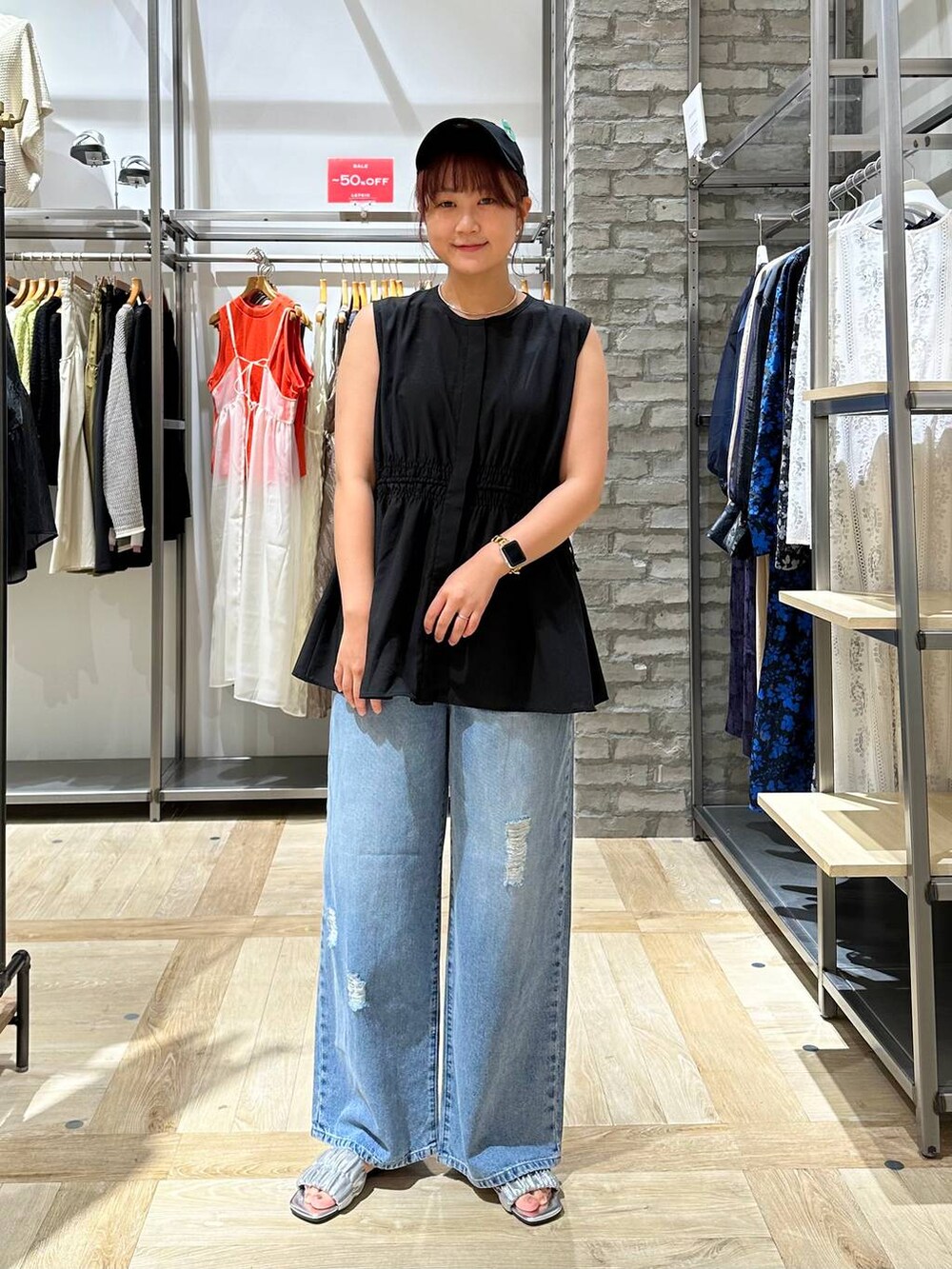 ブルー系のデニムパンツ、ブラック系のショルダーバッグ、グレー系のサンダルを着用したレディースの夏コーディネートの2枚目の写真