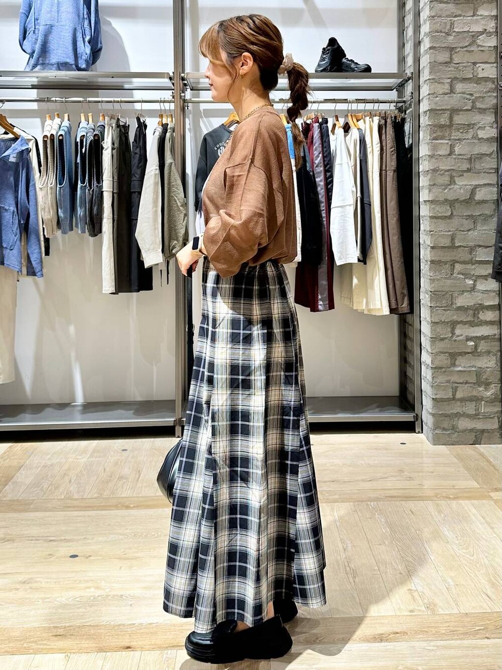 ブラウン系のニット/セーター、ブラック系のスカート、ブラック系のスニーカーを着用したレディースの秋コーディネートの2枚目の写真