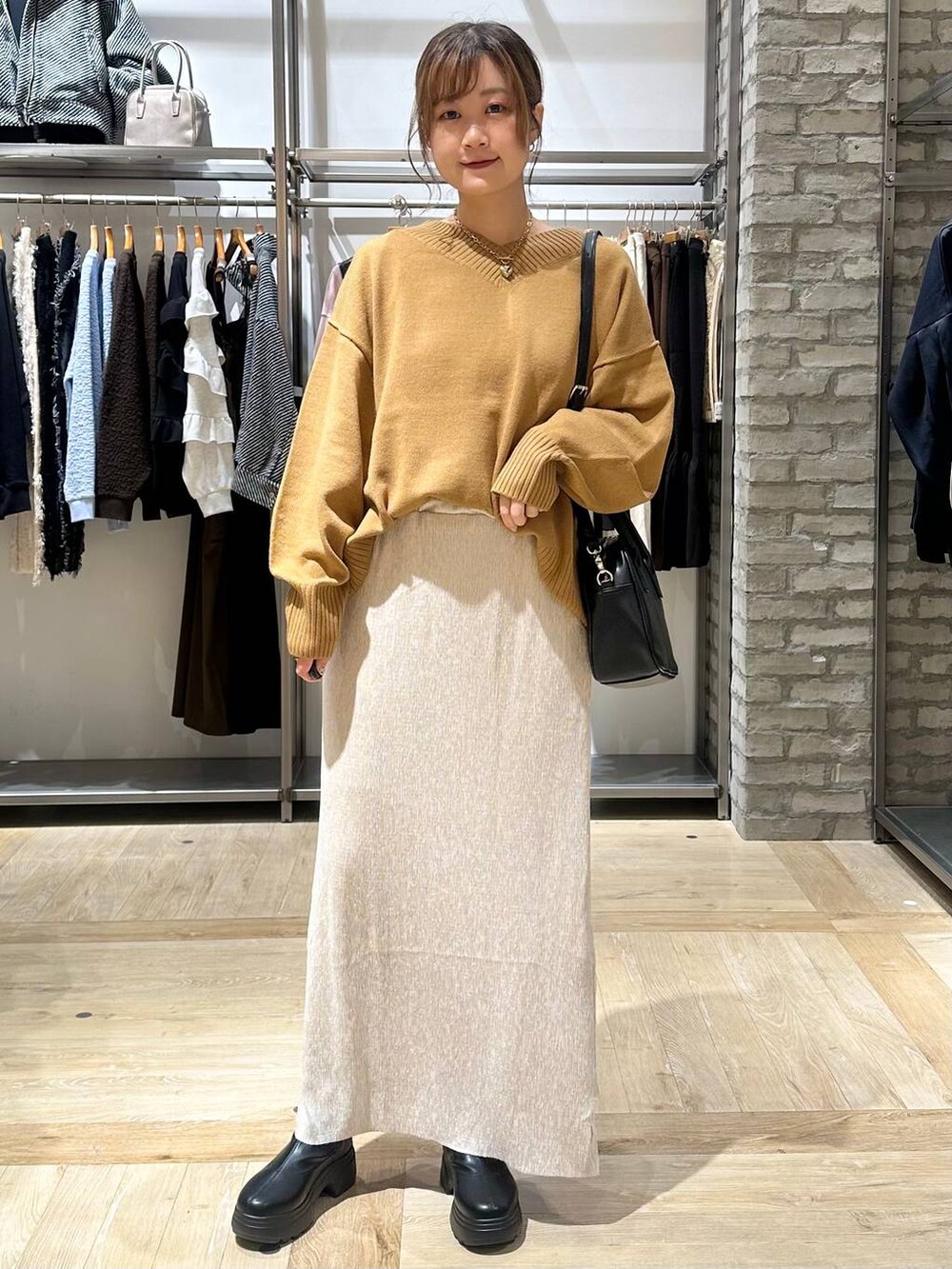 イエロー系のニット/セーター、ブラック系のボストンバッグ、ブラック系のブーツを着用したレディースの秋コーディネートの6枚目の写真