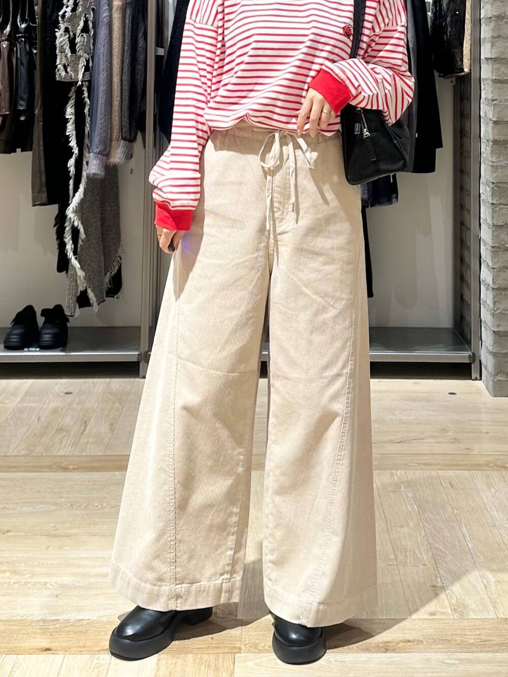 レッド系のTシャツ/カットソー、ブラック系のサンダル、ホワイト系のその他パンツを着用したレディースの秋コーディネートの6枚目の写真