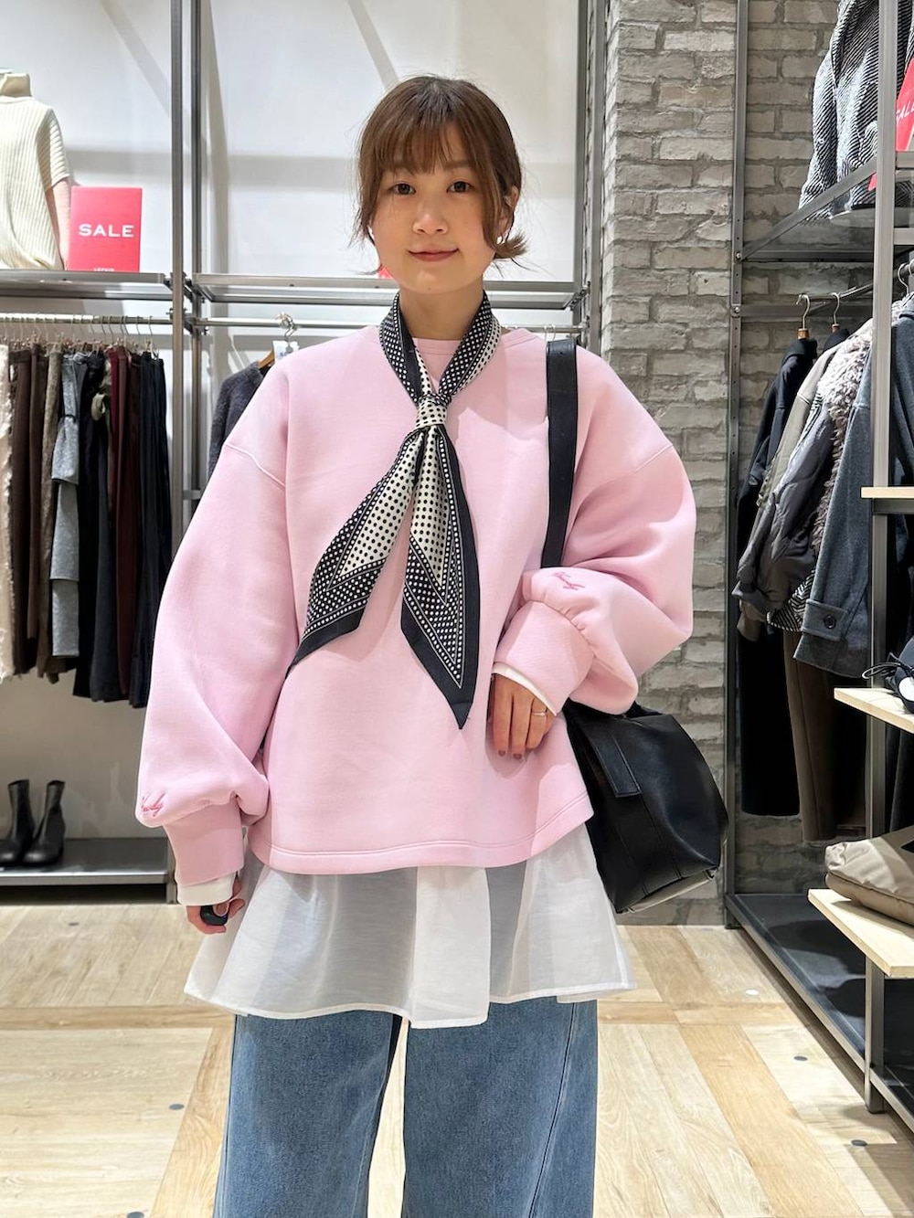 ブラック系のショルダーバッグ、ホワイト系のTシャツ/カットソー、ブラック系のブーツを着用したレディースの冬コーディネートの4枚目の写真