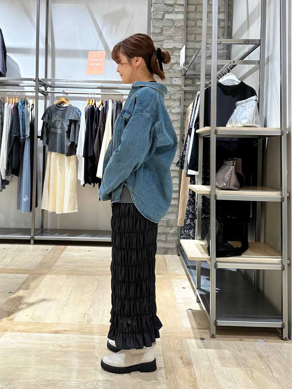 ブラック系のスカート、ホワイト系のブーツ、ブルー系のシャツ/ブラウスを着用したレディースの秋コーディネートの2枚目の写真