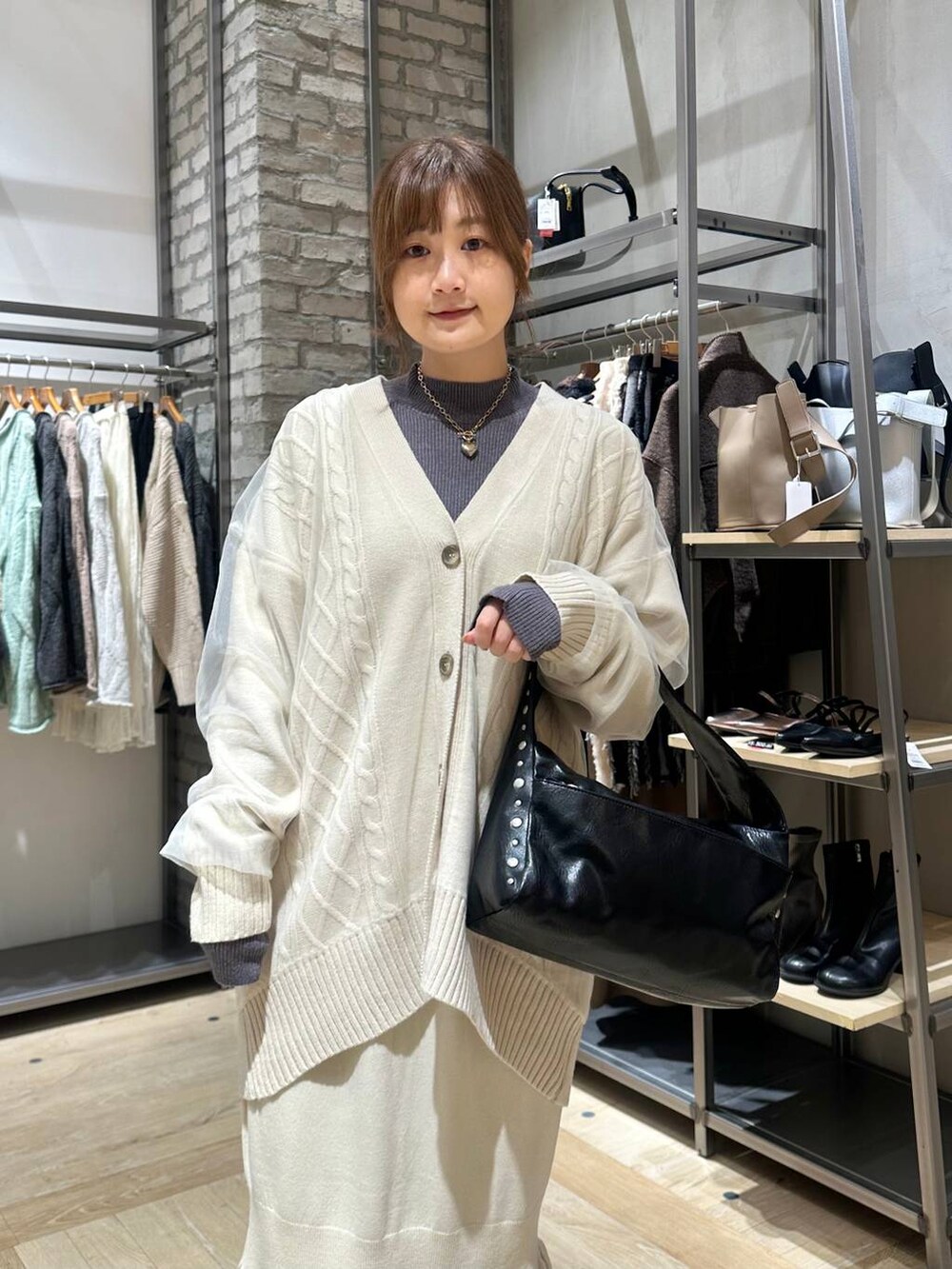 ホワイト系のスカート、グレー系のニット/セーター、ブラック系のブーツを着用したレディースの秋コーディネートの4枚目の写真