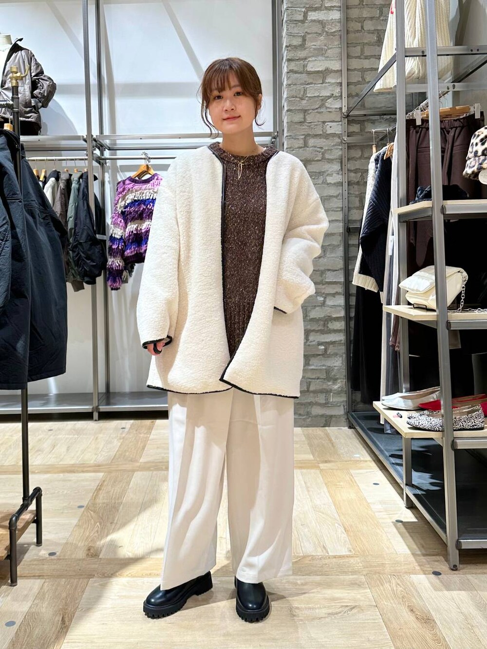 ブラック系のブーツ、ホワイト系のショルダーバッグ、ブラック系のニット/セーターを着用したレディースの秋コーディネートの4枚目の写真