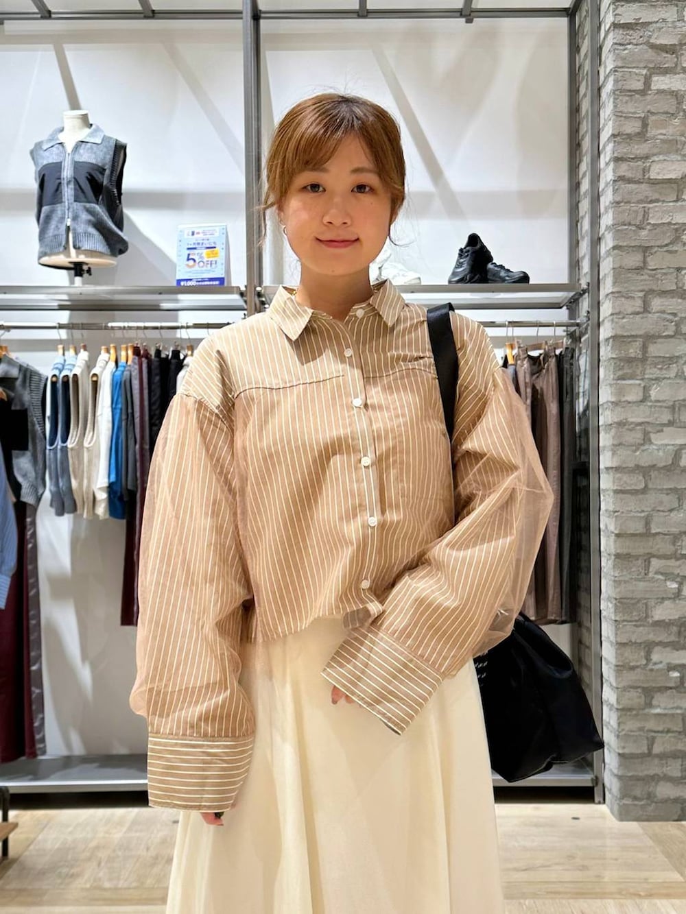 ブラック系のショルダーバッグ、ホワイト系のスカート、イエロー系のシャツ/ブラウスを着用したレディースの秋コーディネートの4枚目の写真