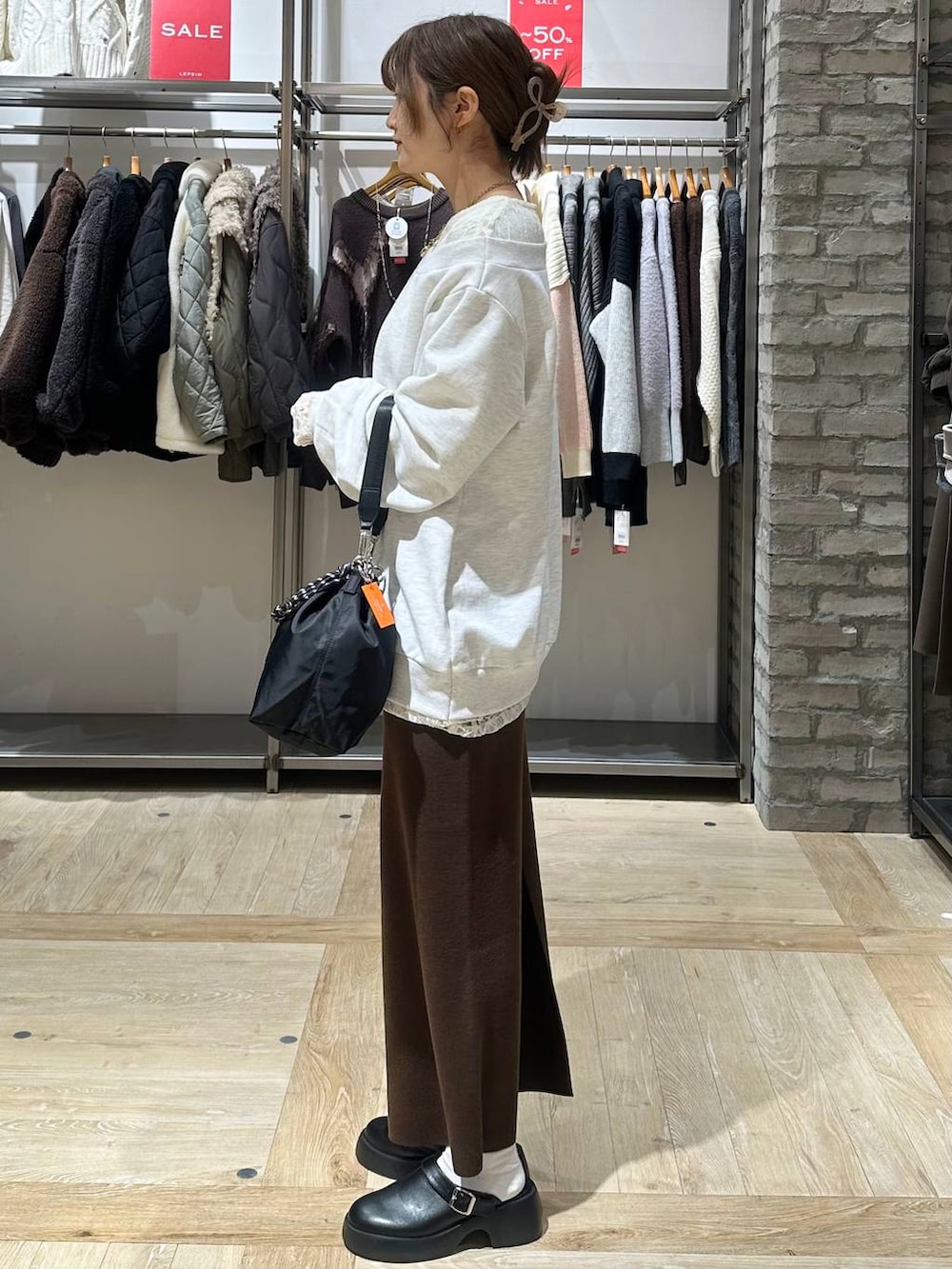 ブラック系のショルダーバッグ、ブラウン系のスカート、ブラック系のサンダルを着用したレディースの冬コーディネートの2枚目の写真