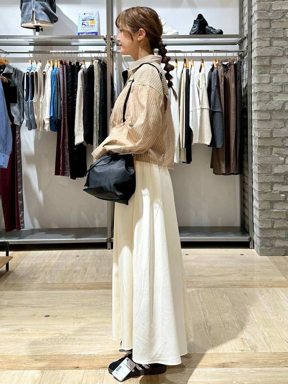 ブラック系のショルダーバッグ、ホワイト系のスカート、イエロー系のシャツ/ブラウスを着用したレディースの秋コーディネートの2枚目の写真