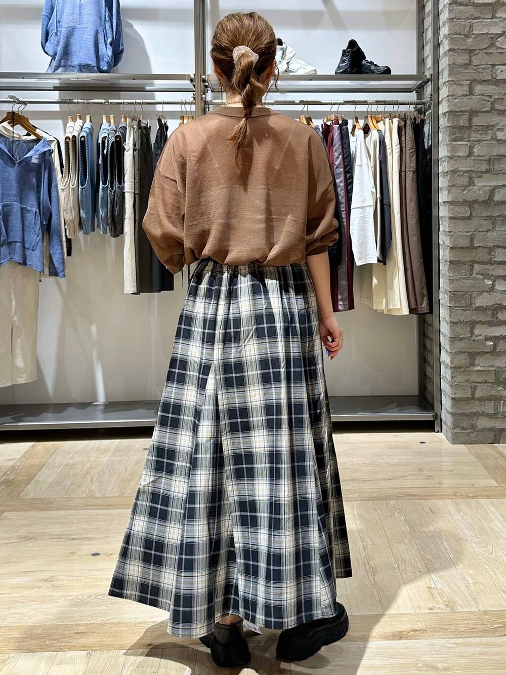 ブラウン系のニット/セーター、ブラック系のスカート、ブラック系のスニーカーを着用したレディースの秋コーディネートの3枚目の写真