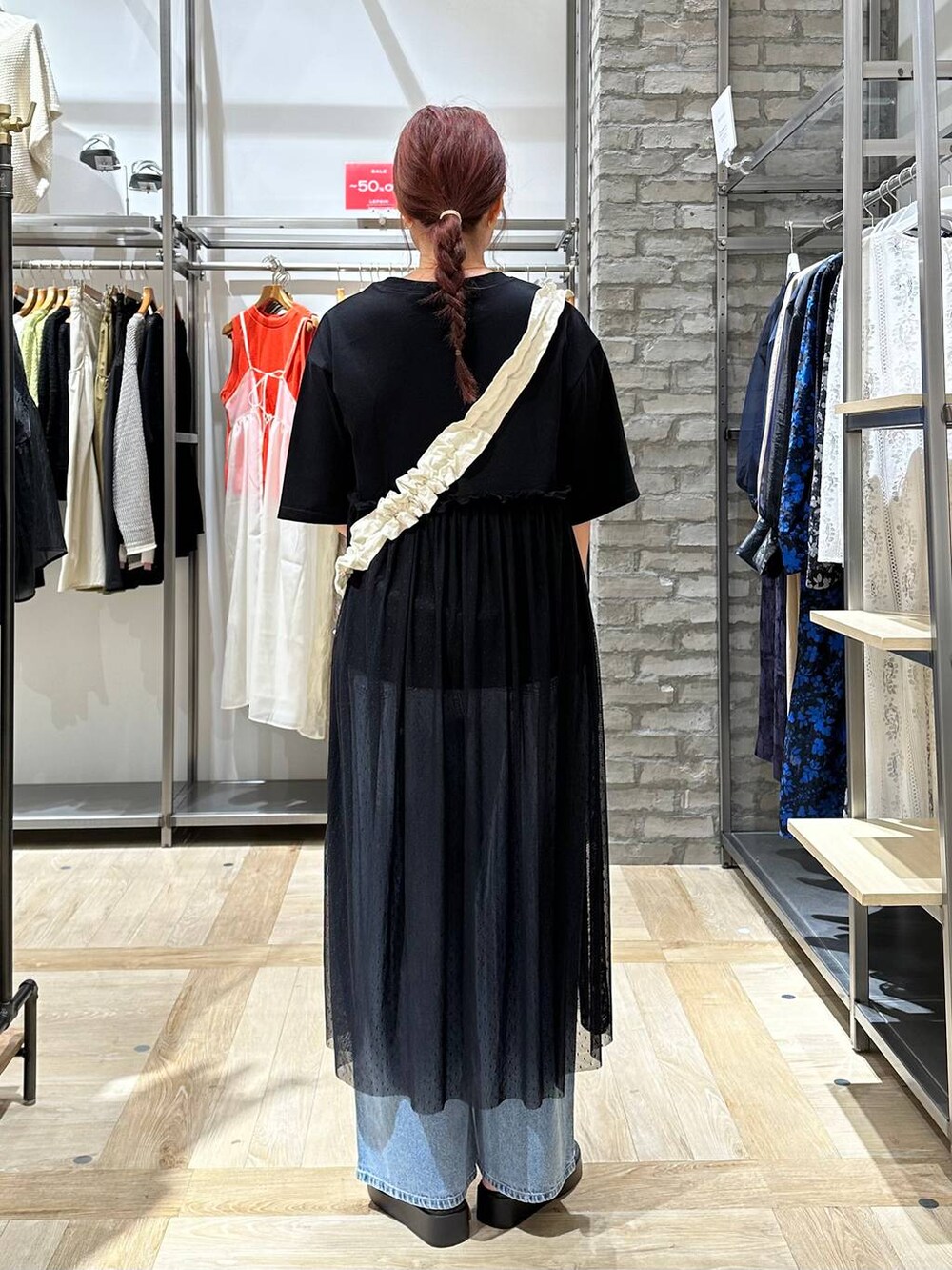 ブルー系のデニムパンツ、ホワイト系のサンダル、ブラック系のワンピースを着用したレディースの夏コーディネートの3枚目の写真
