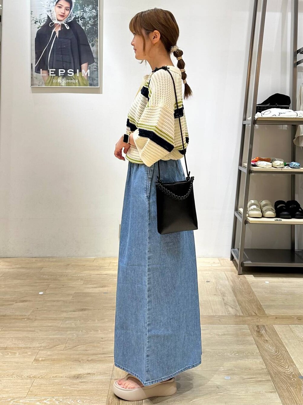 ブルー系のデニムパンツ、ベージュ系のサンダル、ブラック系のショルダーバッグを着用したレディースの夏コーディネートの2枚目の写真