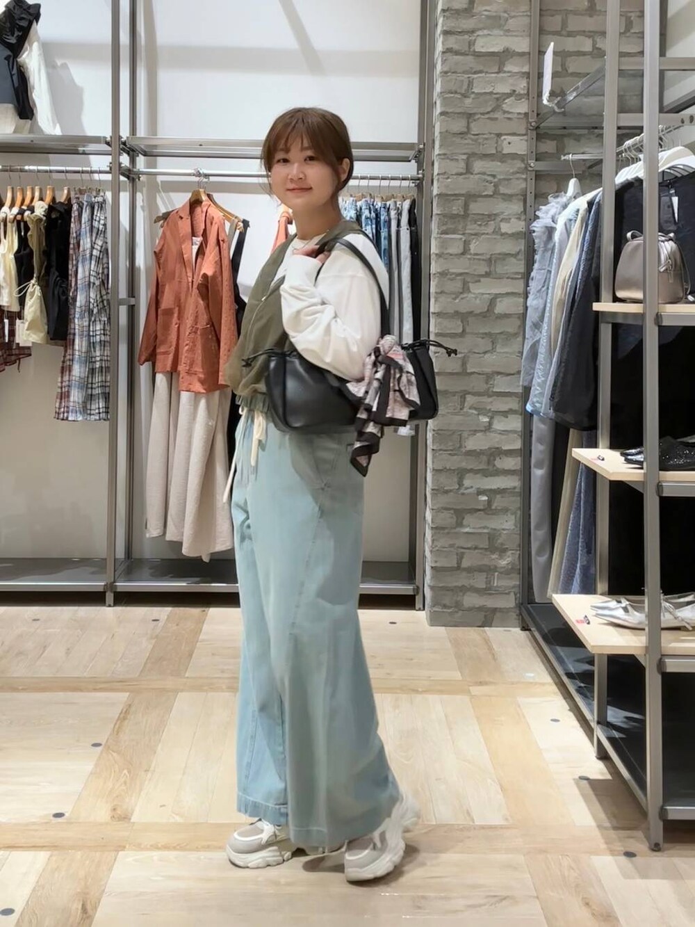 ブラック系のショルダーバッグ、ホワイト系のTシャツ/カットソー、ブルー系のデニムパンツを着用したレディースの春コーディネートの2枚目の写真