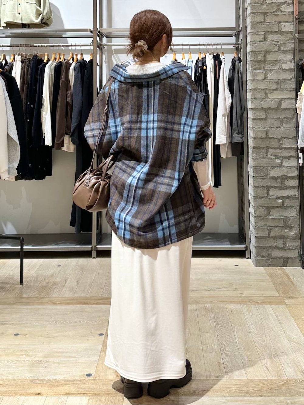 ブラウン系のショルダーバッグ、ブラウン系のブーツ、ホワイト系のTシャツ/カットソーを着用したレディースの秋コーディネートの3枚目の写真