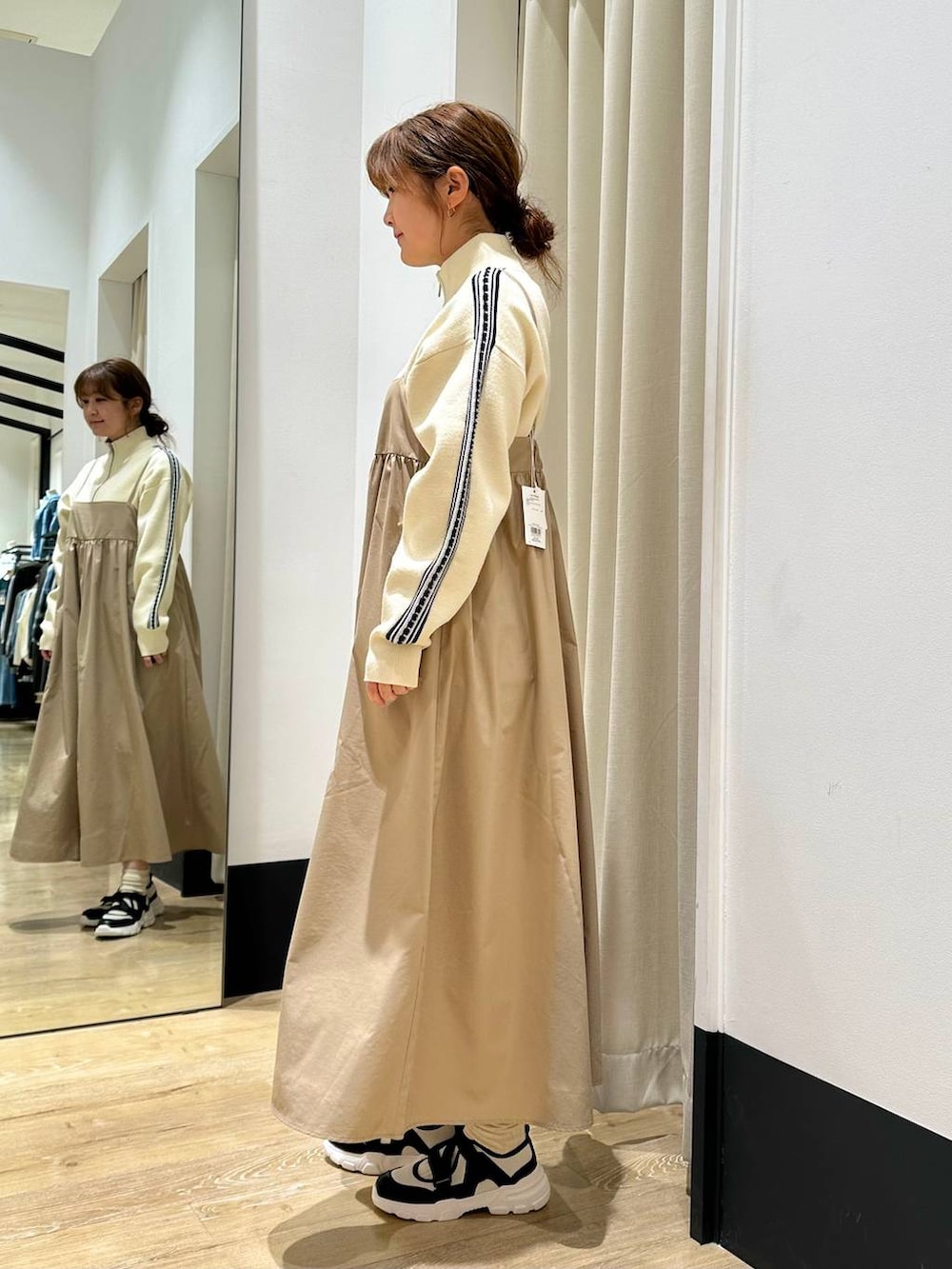 ベージュ系のワンピース、ブラック系のその他アウター、ホワイト系のスニーカーを着用したレディースの冬コーディネートの6枚目の写真