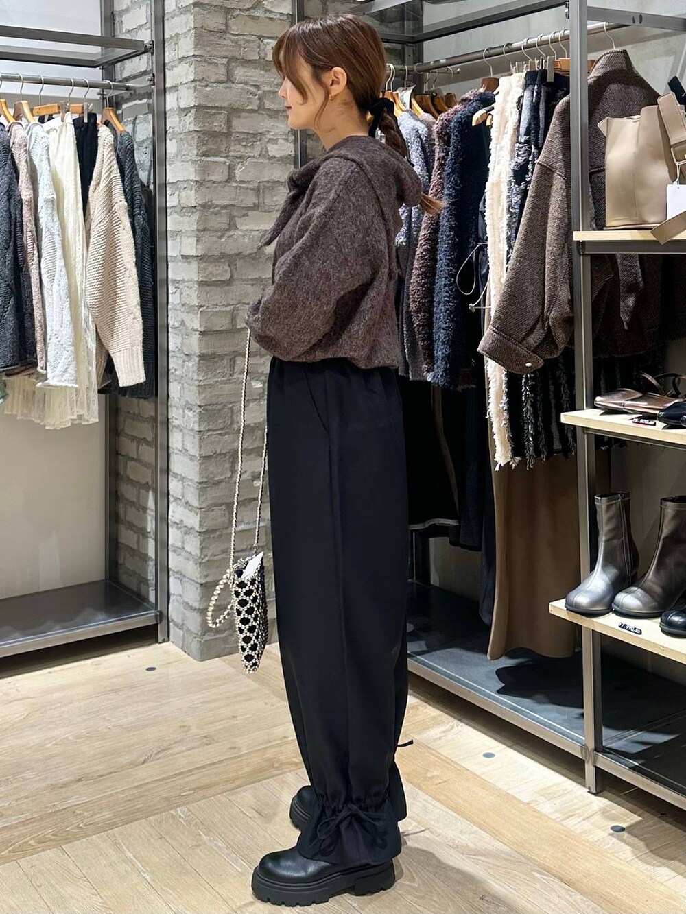 シルバー系のショルダーバッグ、ブラック系のその他パンツ、ブラック系のブーツを着用したレディースの秋コーディネートの2枚目の写真