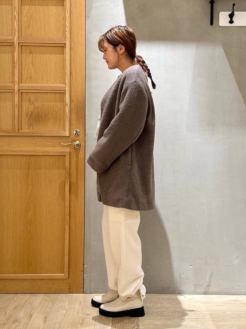 ブラウン系のノーカラーコート、ホワイト系のブーツ、ホワイト系のショルダーバッグを着用したレディースの秋コーディネートの3枚目の写真