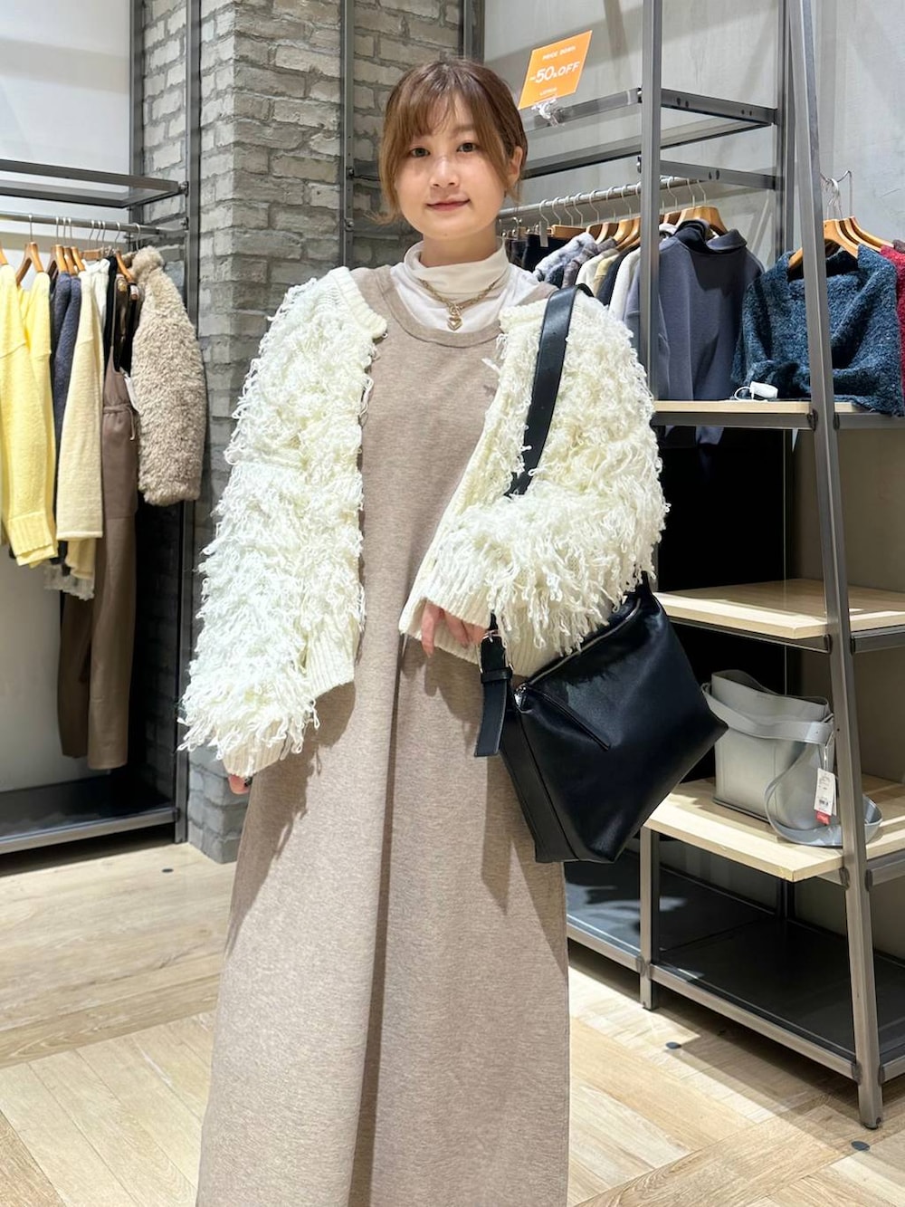 ホワイト系のTシャツ/カットソー、ブラック系のショルダーバッグ、ホワイト系のニット/セーターを着用したレディースの冬コーディネートの5枚目の写真