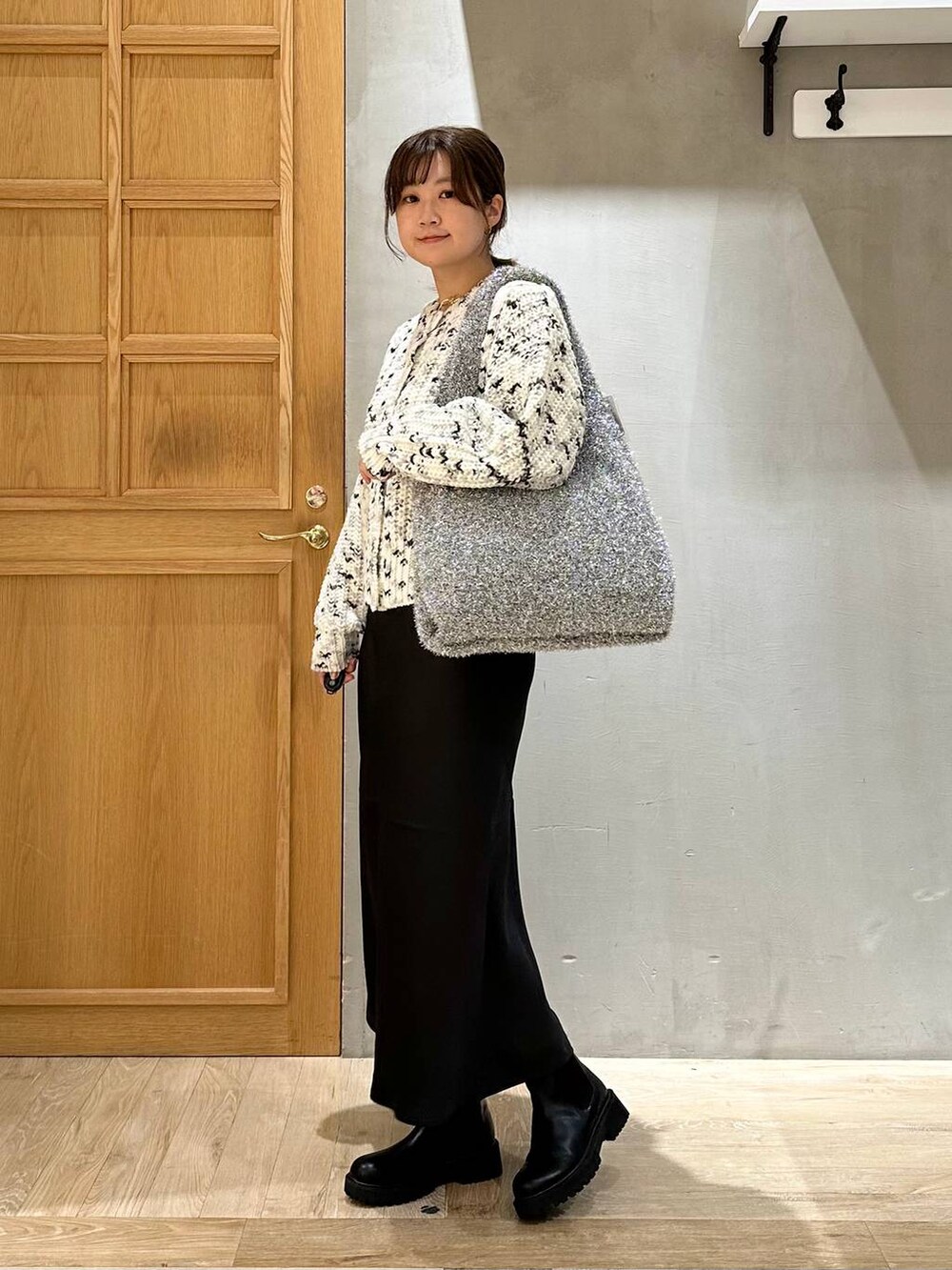 シルバー系のショルダーバッグ、ブラック系のスカート、ブラック系のブーツを着用したレディースの秋コーディネートの2枚目の写真