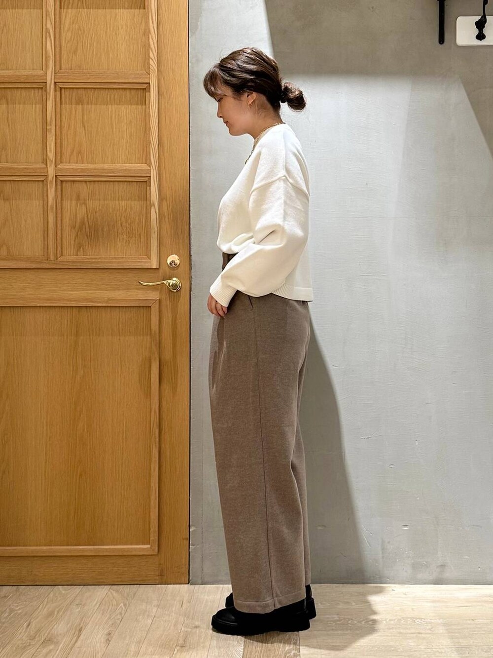 ベージュ系のショルダーバッグ、ブラック系のブーツ、ホワイト系のニット/セーターを着用したレディースの冬コーディネートの3枚目の写真